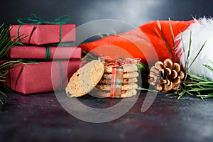 Delicious shortbread cookies with pieces of chocolate, with red ribbon, a sprig of spruce, Santa`s hat, a shortie on a dark photo