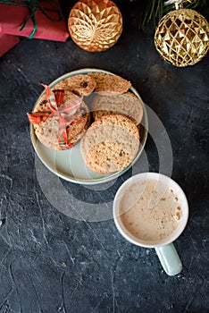 Delicious shortbread with pieces of chocolate in a small plate, aromate coffee, toys on the Christmas tree, sprigs of spruce,