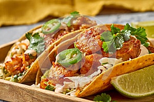 Delicious shrimp tacos on wooden tray with lime slices