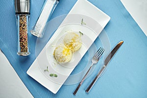 Delicious side dish for main courses - mashed potatoes with parmesan in cream in a white plate on a blue tablecloth