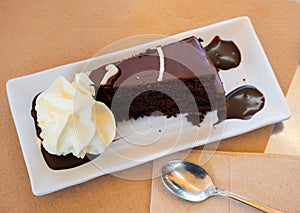 Delicious slice of brownie cake on plate with whipped cream