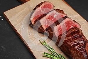 Delicious sliced beef tenderloin on black table, closeup