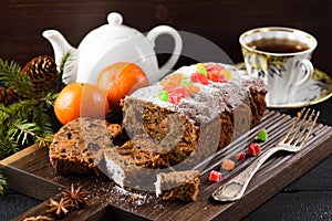 Delicious sliced fruit cake on wooden board served with tea and