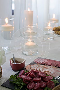 Delicious sliced Portuguese sausages elegantly arranged near candles on a wedding table.