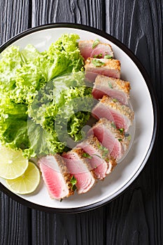 Delicious sliced tuna steak fried in breading served with leaf s