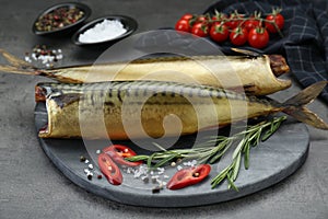 Delicious smoked mackerels and spices on dark grey table