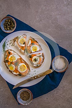 Delicious smoked salmon sourdough toast with goat cream cheese and cut boiled egg, garnished with dill, chives & pickled Capers