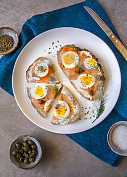 Delicious smoked salmon sourdough toast with goat cream cheese and cut boiled egg, garnished with dill, chives & pickled Capers
