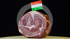 Delicious smoked tenderloin with small flag of Hungary, piece of meat rotating on balck background.