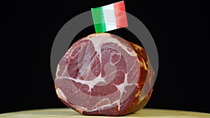 Delicious smoked tenderloin with small flag of Italy, piece of meat rotating on balck background.