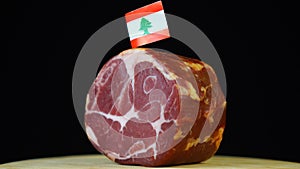 Delicious smoked tenderloin with small flag of lebanon, piece of meat rotating on balck background.