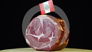 Delicious smoked tenderloin with small flag of Peru, piece of meat rotating on balck background.