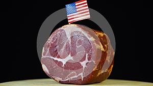 Delicious smoked tenderloin with small flag of USA, piece of meat rotating on balck background.