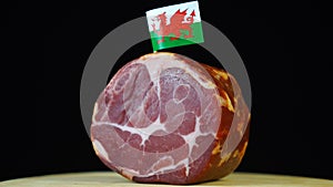 Delicious smoked tenderloin with small flag of Wales, piece of meat rotating on balck background.