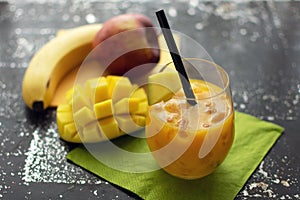 Delicious smoothie with mango in a glass with crushed ice and straw