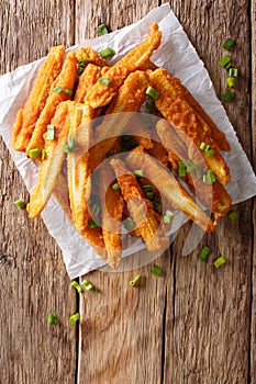 Delicious snack of fried baby corn close-up on the table. Vertical top view