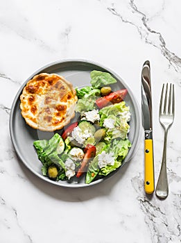 Delicious snack - mini canned tuna, mozzarella quiche and Greek salad on a light background, top view