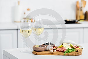 delicious snacks on wooden board and glasses of wine on table