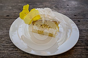 Delicious soft sweet white fresh coconut cake with beautiful yellow trumpet flower decoration on white ceramic plate on wooden