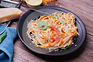Delicious spaghetti pasta with prawns and cheese served in a black bowl on a black background table Italian recipe, tomato sauce,