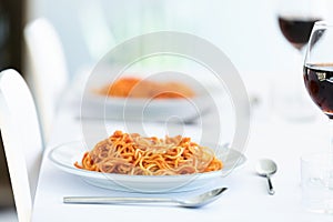 Delicious spaghetti with tomatoe sauce served on a white plate on the kitchen at home