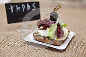 Delicious Spanish tapas, with a rustic mozzarella and dried tomato with olive. TAPAS poster .