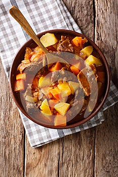 delicious stew estofado with beef and vegetables close-up. Vertical top view photo