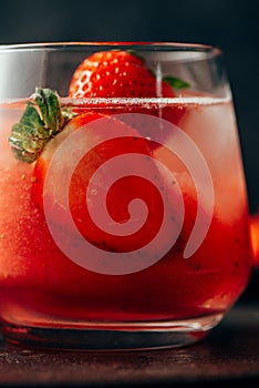 Delicious strawberry cocktail with ice on dark background