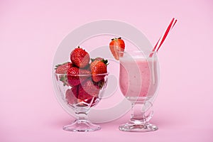 Delicious strawberry milkshake in glass with straw and fresh strawberries in bowl