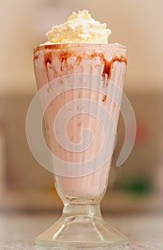 Delicious strawberry milkshake with syrup and cream on top