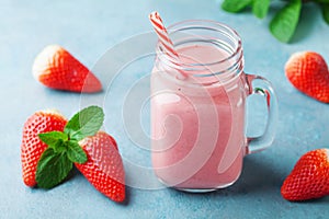 Delicious strawberry smoothie or milkshake in mason jar on turquoise table. Healthy food for breakfast and snack.
