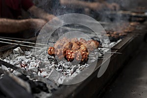 Delicious street food chicken on a bbq with smokes, close up