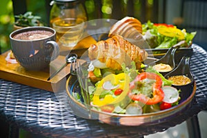 Delicious and stylish served table with coffee and tea, croissant and greens at breakfast