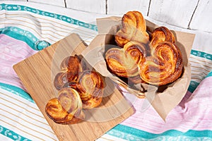 Delicious sugar buns in a wicker basket with paper and on a wooden board. Homemade baking