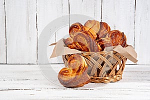 Delicious sugar buns in a wicker basket with paper and on a wooden board. Homemade baking