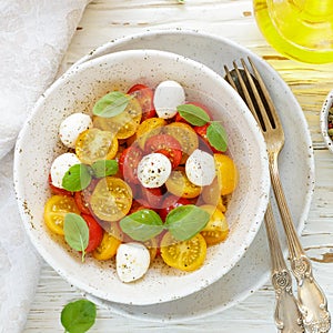 Delicious summer salad of yellow and red cherry tomatoes, mozzarella with Basil