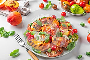 Delicious summer warm salad with grilled peaches, vegetables and cheese on white background