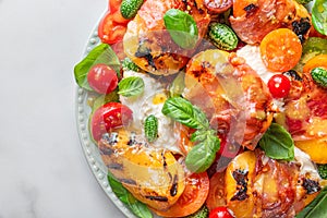 Delicious summer warm salad with grilled peaches, vegetables and cheese on white background. Close up