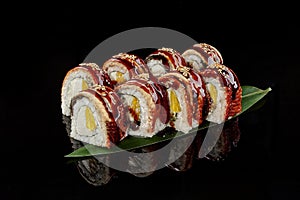 Sushi rolls with eel, cream cheese and orange on bamboo leaf photo