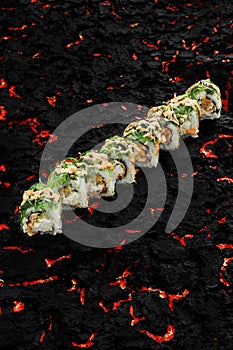 Delicious sushi rolls with rice, chuka and fish on black stone background