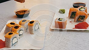 Delicious sushi with salmon, cheese, wasabi, pink ginger, soy sauce Which are taken with wooden sticks on a stylish