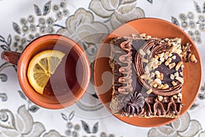 Delicious and sweet chocolate cake with cream and nuts and a Ñup of black tea with lemon