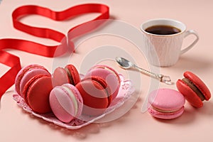 Delicious sweet macaroons in a figural plate on a pink background, red and pink macaroons