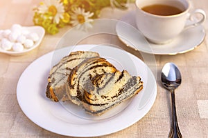 Delicious sweet poppy seed cake on a plate, on a table and a Cup of tea.