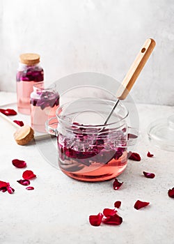 Delicious sweet rose syrup in a glass cooking pot with pink petals in it.