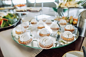 Delicious sweet white cakes on a mirror tray in a restaurant. Food for dessert