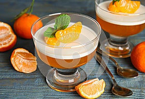 Delicious tangerine jelly and fresh fruits on light blue wooden table, closeup