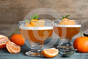 Delicious tangerine jelly and fresh fruits on light blue wooden table, closeup