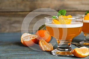 Delicious tangerine jelly and fresh fruits on light blue wooden table, closeup