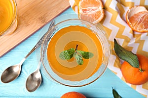 Delicious tangerine jelly and fresh fruits on light blue wooden table, flat lay